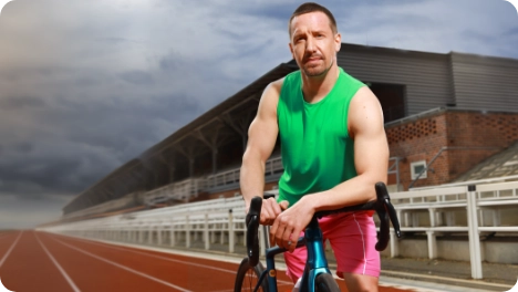 Foto eines männlichen Athleten mit seinem Fahrrad auf einer Laufbahn