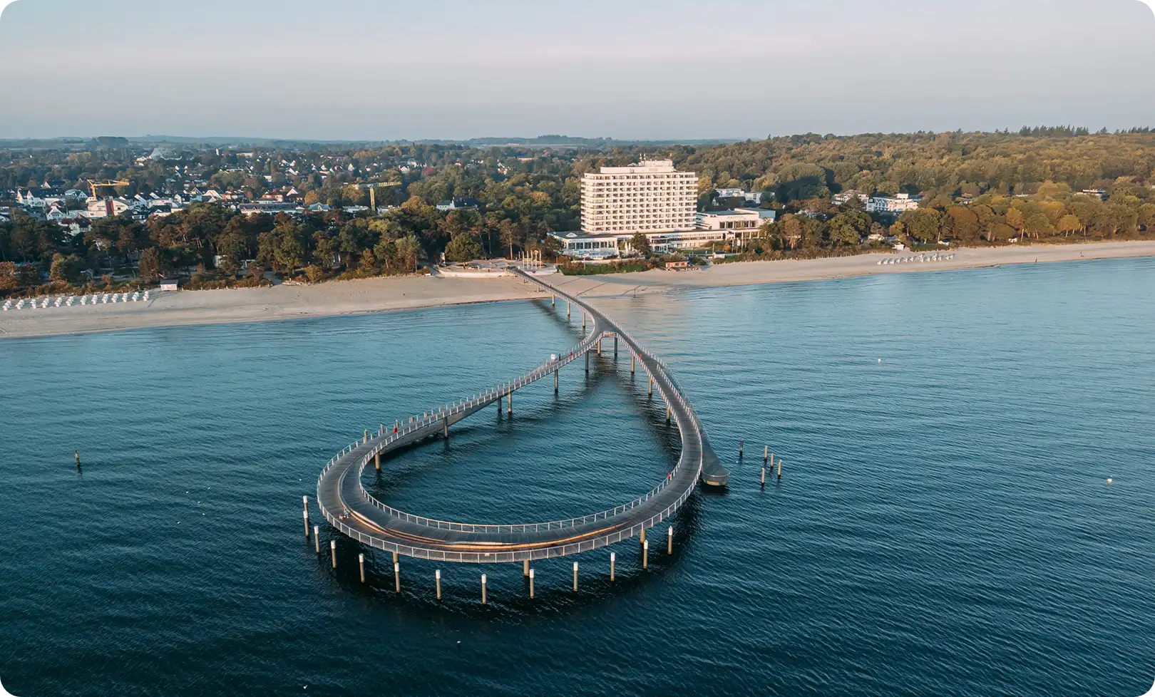 Geschwungene Seebrücke an der Ostsee mit Strand und Hotel